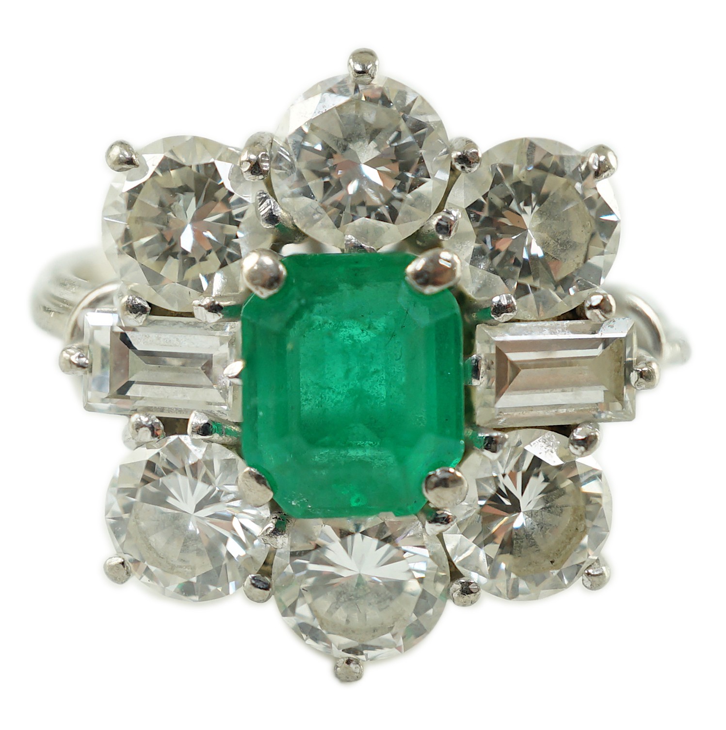 A mid 20th century 18kt white gold, single stone emerald and round and baguette cut diamond cluster ring